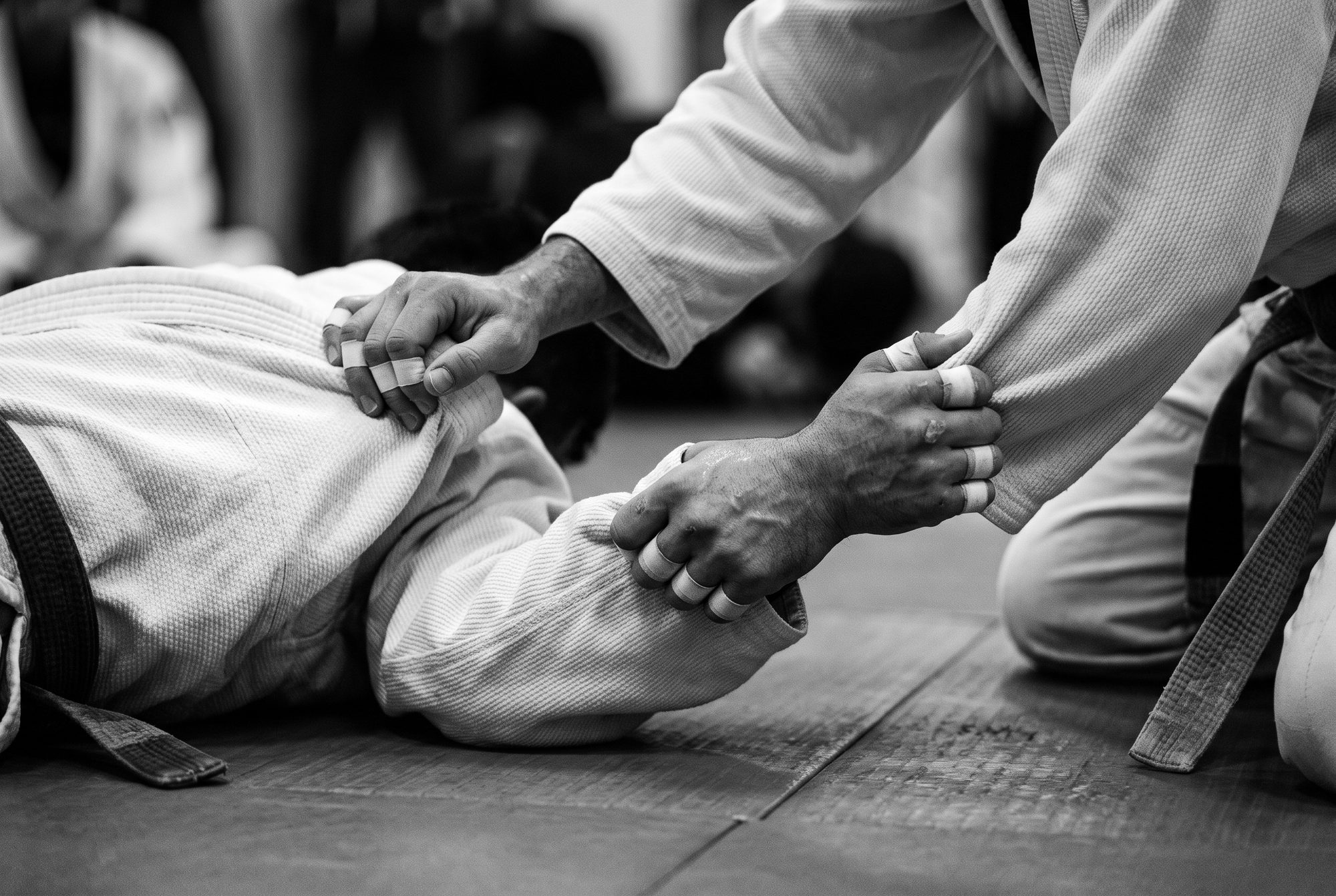 Close-up of hands gripping the collar and sleeve of a jiu-jitsu gi