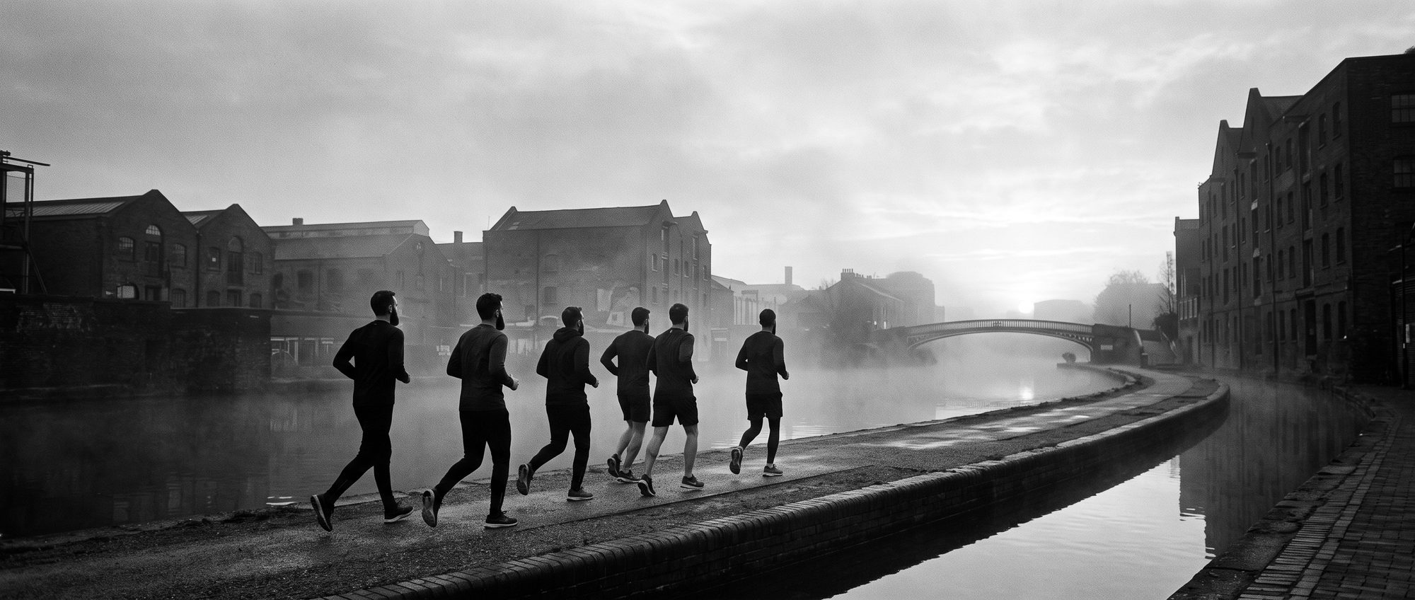 Brothers running together along a misty canal towpath at dawn